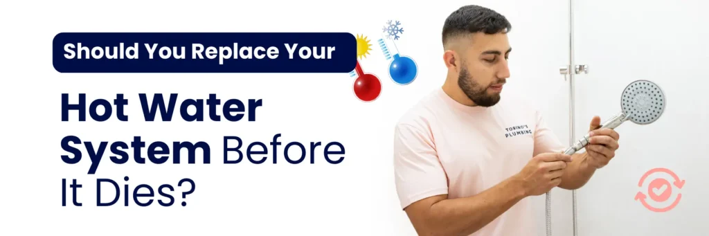 A person holds a showerhead in a bathroom, illustrating the importance of replacing hot water systems before failure occurs.