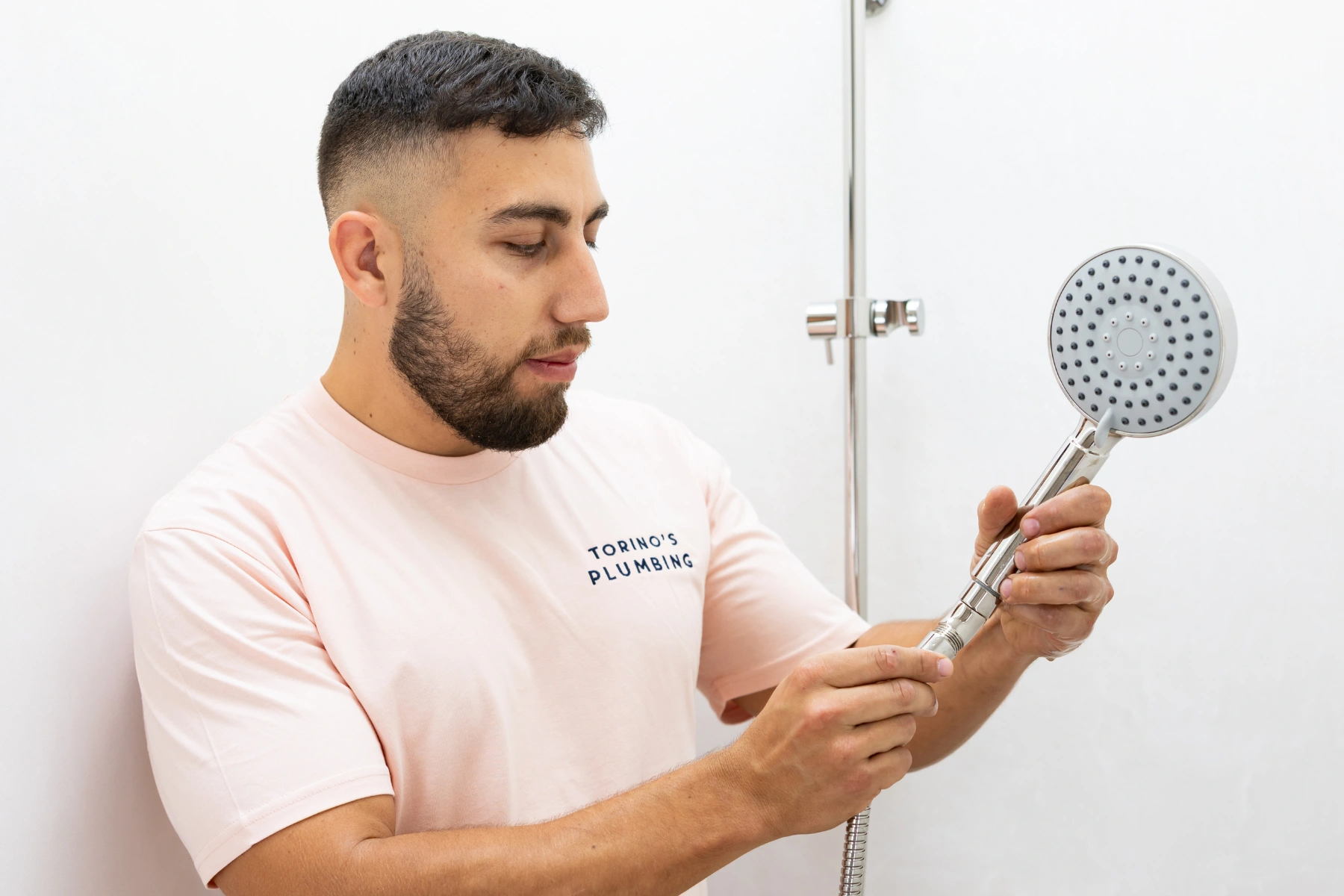 Guy plumber fixing a showerhead for the bathroom